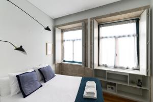 a bedroom with a bed and two windows at Maria da Sé Historic House in Porto