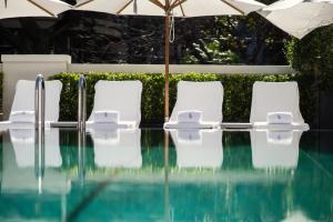 4 sillas blancas y una sombrilla junto a la piscina en Four Seasons Hotel Buenos Aires en Buenos Aires