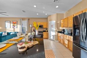 a large kitchen with a table and a refrigerator at Pool - Life Size Games - 25 mins to Disney World in Davenport