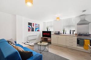 Boutique Nottingham Abode - Sleeps 6 في نوتينغهام: غرفة معيشة مع أريكة زرقاء ومطبخ