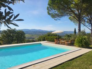 a swimming pool with a table and an umbrella at Villa with Pool and Countryside View in Montefalco