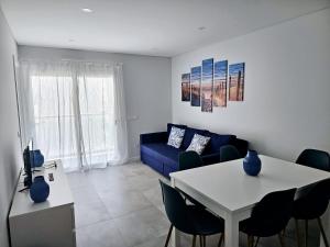 een woonkamer met een blauwe bank en een tafel bij Apartment Dona Vitória - Monte Gordo Beach in Monte Gordo