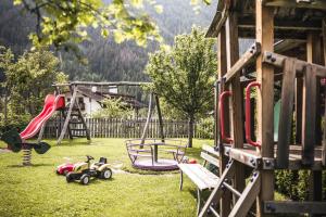 einen Spielplatz mit Rutsche und Spielausrüstung im Gras in der Unterkunft Familienhotel Viktoria in Ulten