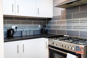 a kitchen with white cabinets and a stove at OnSiteStays - Contractor Friendly Retreat, 2-BR Terrace House near A2 in Gravesend