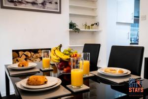 - une table avec des assiettes de nourriture et un bol de fruits dans l'établissement OnSiteStays - Contractor Friendly Retreat, 2-BR Terrace House near A2, à Gravesend