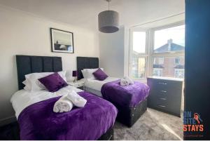 - une chambre avec 2 lits avec des draps violets et une fenêtre dans l'établissement OnSiteStays - Contractor Friendly Retreat, 2-BR Terrace House near A2, à Gravesend