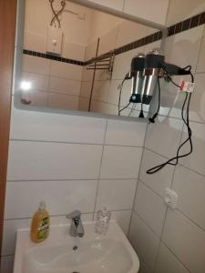 ein weißes Badezimmer mit einem Waschbecken und einem Spiegel in der Unterkunft City Pension Senftenberg / Apartment Nr.1 in Senftenberg