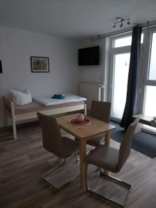 ein Wohnzimmer mit einem Tisch, Stühlen und einem Bett in der Unterkunft City Pension Senftenberg / Apartment Nr.1 in Senftenberg