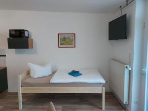 Bett in einem Zimmer mit einem TV an der Wand in der Unterkunft City Pension Senftenberg / Apartment Nr.1 in Senftenberg