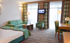 a hotel room with a bed and chairs and a television at Flamingo Grand Hotel & Spa in Albena