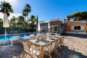 a patio with a table and chairs next to a pool at Villa Sea, Sun and Golf in Vilamoura in Quarteira