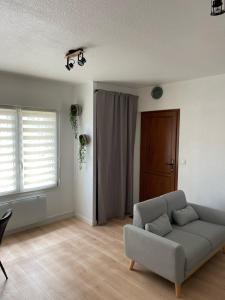 sala de estar con sofá y ventana en Appart avec chambre lumineux et chaleureux, en Le Boulou