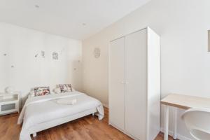 a white bedroom with a bed and a sink at Appartement budget avec parking au centre-ville in Charleville-Mézières