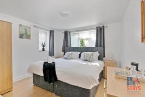 um quarto com uma cama grande e lençóis brancos em OnSiteStays - Tranquil 2 Bedroom Apartment with Large Kitchen, Private Garden near Wimbledon Station em Londres