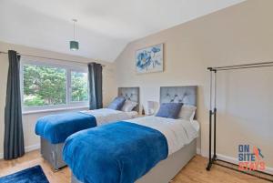 two beds in a bedroom with a window at OnSiteStays - Comfortable Contractor Accommodation, 3-BR House, WIFI, Parking & Large Garden in Enfield Lock
