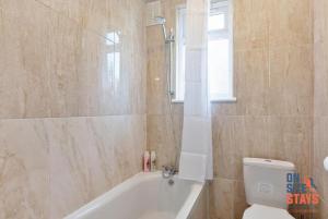 a bathroom with a tub and a toilet and a window at OnSiteStays - Comfortable Contractor Accommodation, 3-BR House, WIFI, Parking & Large Garden in Enfield Lock