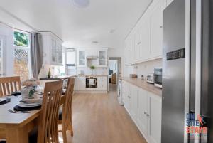 uma cozinha com armários brancos, uma mesa e um frigorífico em OnSiteStays - Tranquil 2 Bedroom Apartment with Large Kitchen, Private Garden near Wimbledon Station em Londres