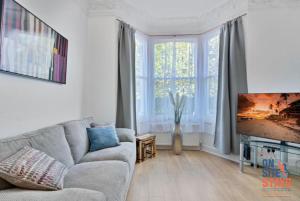 a living room with a couch and a large window at OnSiteStays - Tranquil 2 Bedroom Apartment with Large Kitchen, Private Garden near Wimbledon Station in London