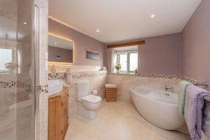 ein Badezimmer mit Badewanne, Toilette und Waschbecken in der Unterkunft 18th century renovated barn in beautiful Devon countryside in Broadwoodwidger