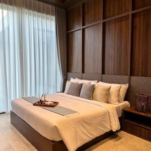 a bedroom with a large bed with a wooden headboard at TANA Beach Villas in Lian