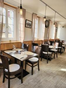 un restaurante con mesas y sillas y un reloj en la pared en Auberge de l’Union en Lens