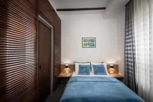 LANTerna Boutique Hotel في Srbac: غرفة نوم بسرير كبير مع شراشف زرقاء