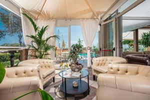 a living room with white furniture and large windows at Hotel Excelsior in Bibione