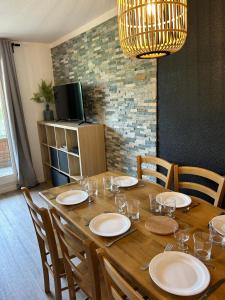 a wooden table with plates and wine glasses on it at APPARTEMENT 310 ECRIN D'HUEZ in L'Alpe-d'Huez