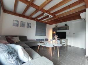 een woonkamer met een bank en een tafel bij Vakantiewoning Polderhuis 10, airco en verwarming in alle kamers, privé parkeerplaats en afgesloten tuin in Koksijde