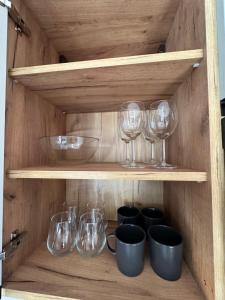 ein Holzregal mit Gläsern, Schalen und Tassen in der Unterkunft Apartamenty 1-maja 94 in Kattowitz