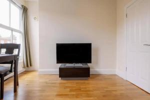 sala de estar con TV de pantalla plana en una pared blanca en Bright and Quiet 2-bed 2-bath with Great Patio en Londres