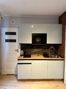 uma cozinha com armários brancos e um lavatório em Apartamenty 1-maja 94 em Katowice