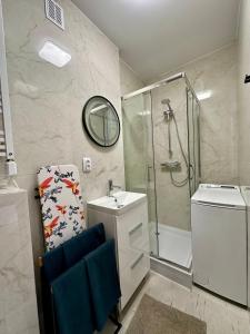 a bathroom with a shower and a sink and a mirror at Apartamenty 1-maja 94 in Katowice