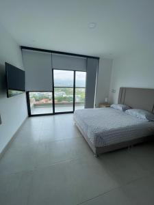 ein Schlafzimmer mit einem Bett und einem großen Fenster in der Unterkunft Apartaestudio de lujo en Cali in Cali