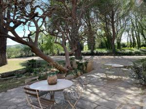 een patio met 2 tafels, stoelen en bomen bij Mas de Clary - propriété de caractère avec PISCINE in Roquemaure