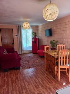 a living room with a table and a red refrigerator at Cabaña valle de elqui horcon Encantó del pimiento in Horcon