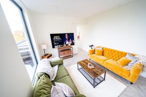 a living room with a yellow couch and a table at Luxurious 4-Bedroom Penthouse: 15 Mins to City Centre, Secure Parking in Leeds
