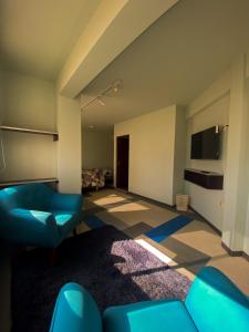 a living room with blue chairs and a television at Posada Mia Copacabana in Copacabana