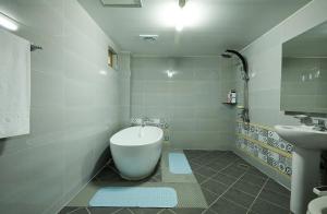 y baño con bañera blanca y lavamanos. en Buan Tree California Hotel en Buan