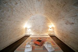 アルベロベッロにあるTrulli di Nonno Carloのレンガの壁にベッドが備わる小さな客室です。