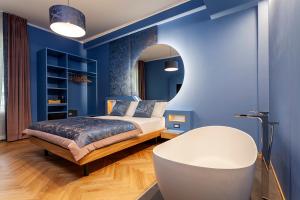 Dormitorio azul con cama y espejo redondo en Le Texture Premium Rooms Duomo-Cordusio, en Milán