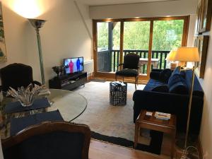 uma sala de estar com um sofá azul e uma televisão em le Pullman em Deauville