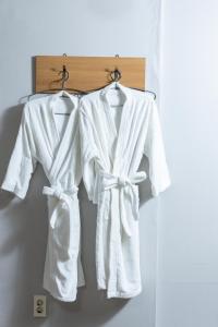 two white robes hanging on a wall at Buan Tree California Hotel in Buan