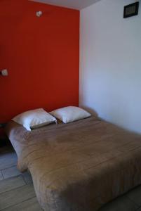 uma cama num quarto com uma parede laranja em Appartement 2 pièces sur jardin en Pic Saint-Loup em Valflaunès