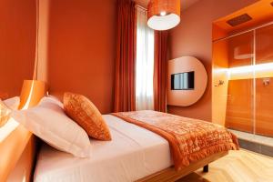 Le Texture Premium Rooms Duomo-Cordusio في ميلانو: غرفة نوم بجدران برتقالية وسرير بمخدات برتقالية