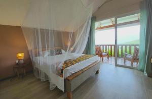 a bedroom with a canopy bed and a balcony at My Paradise in Baie Lazare Mahé