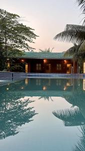 a swimming pool in front of a house at Hrishivan Resort Nagaon in Nagaon
