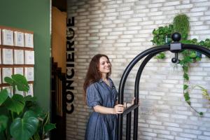 une femme debout devant un mur de briques tenant une porte dans l'établissement The Circus Apartments, à Berlin