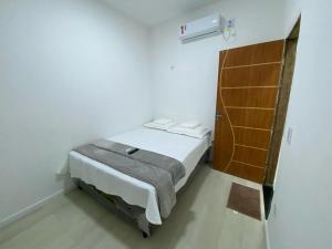 a small white bedroom with a bed in a room at Alemanha aconchego in São Luís