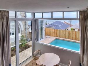 a room with a pool and a table and a window at The Dragon Tree Guesthouse in Kalk Bay